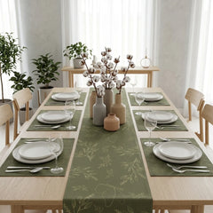 Dining table set with green tablecloth, white plates, and decorative vases in a bright room.